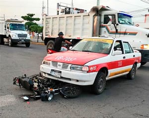 ¡MOTORIZADO QUEDÓ BAJO LAS LLANTAS DEL TAXI!